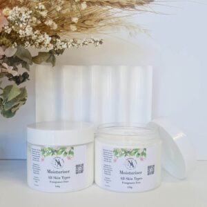 Northern Aroma fragrance-free moisturisers displayed in white jars against a soft, neutral backdrop. One jar is closed while the other is open, showing the creamy texture inside. Dried botanical stems in natural tones hang from the top left, adding an earthy, minimal aesthetic.”